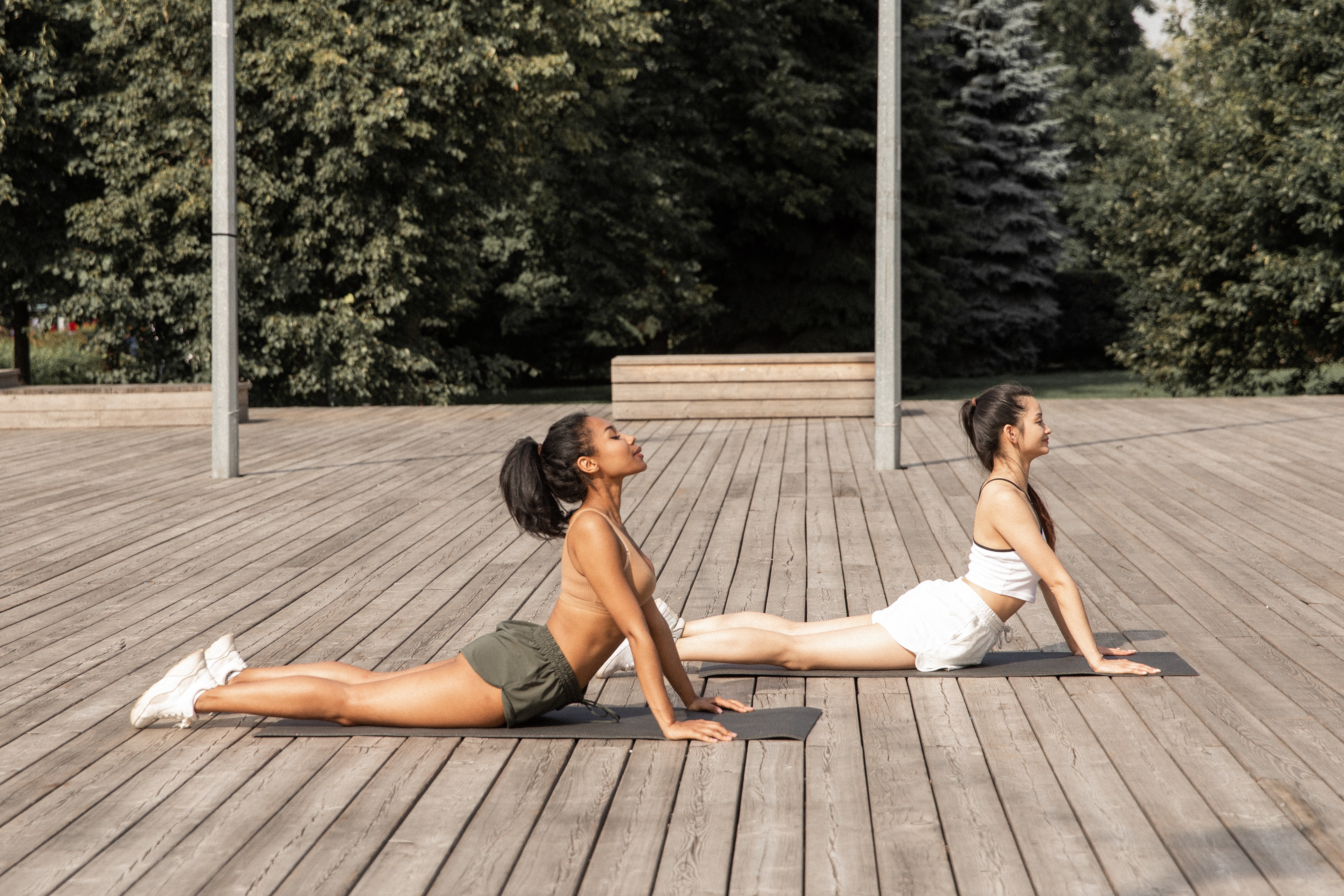 Two ladies doing cobra yoga pose on mat.
